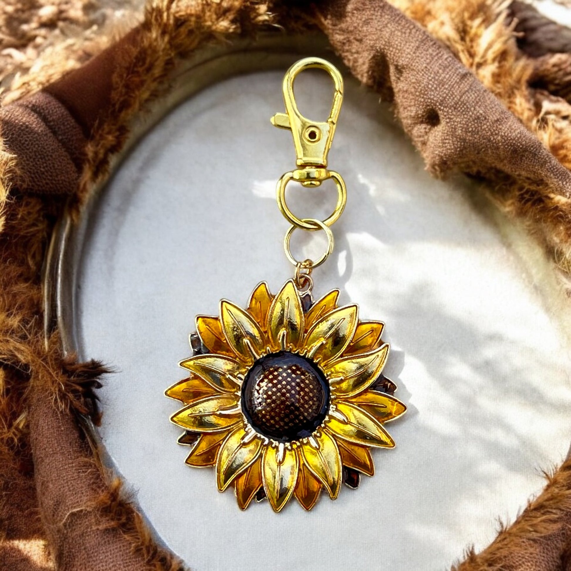 Gold sunflower keychain displayed with brown rustic fabric