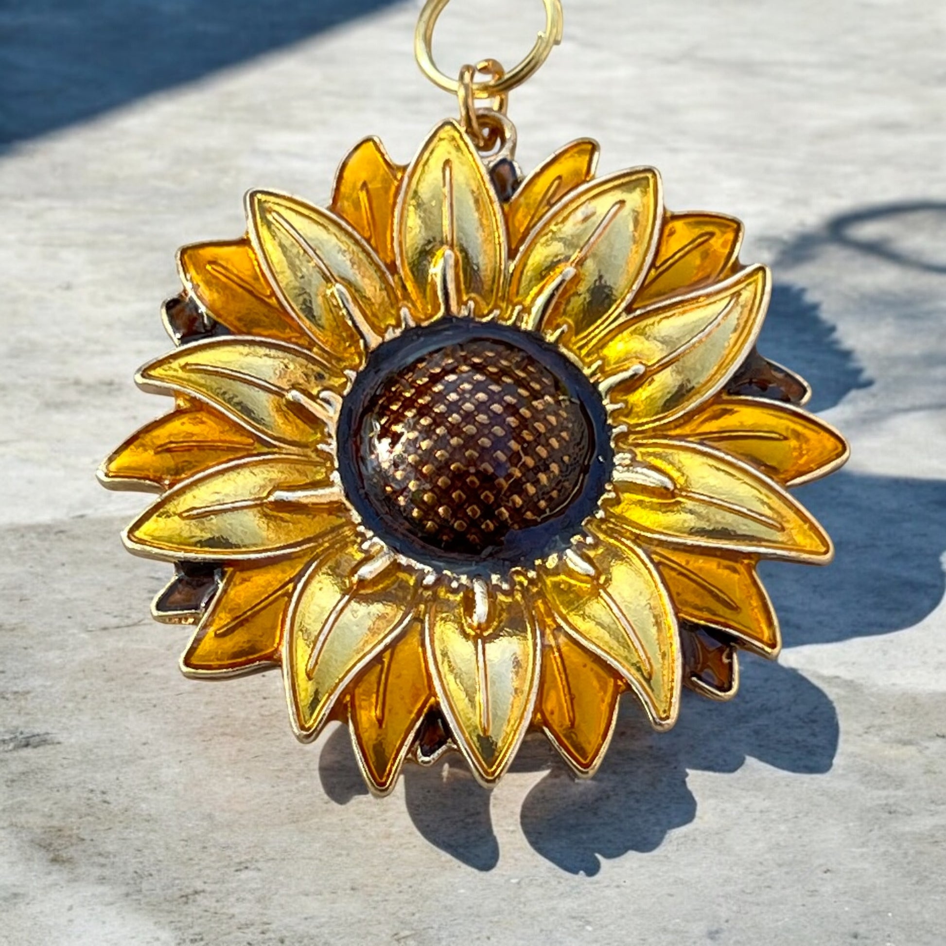Sunflower charm with golden petals on patterned fabric background