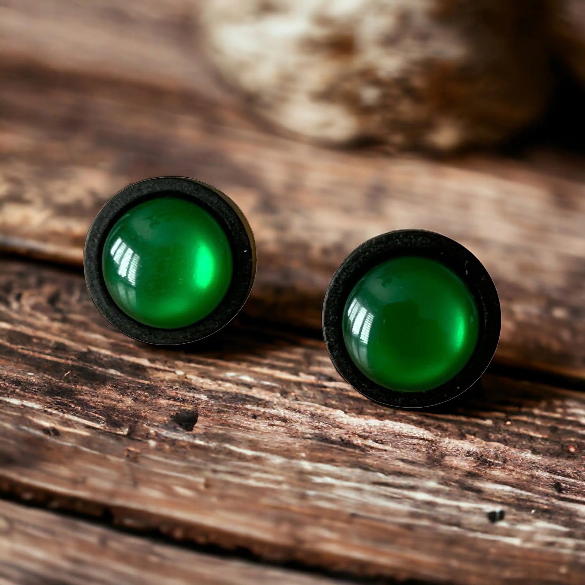 Green stud earrings on a wooden surface