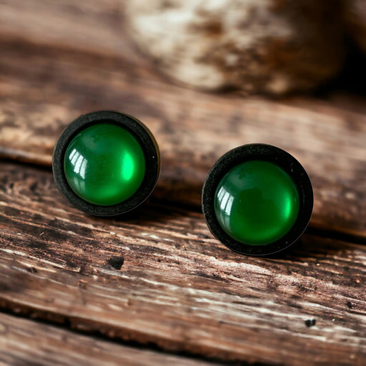 Green stud earrings on a wooden surface