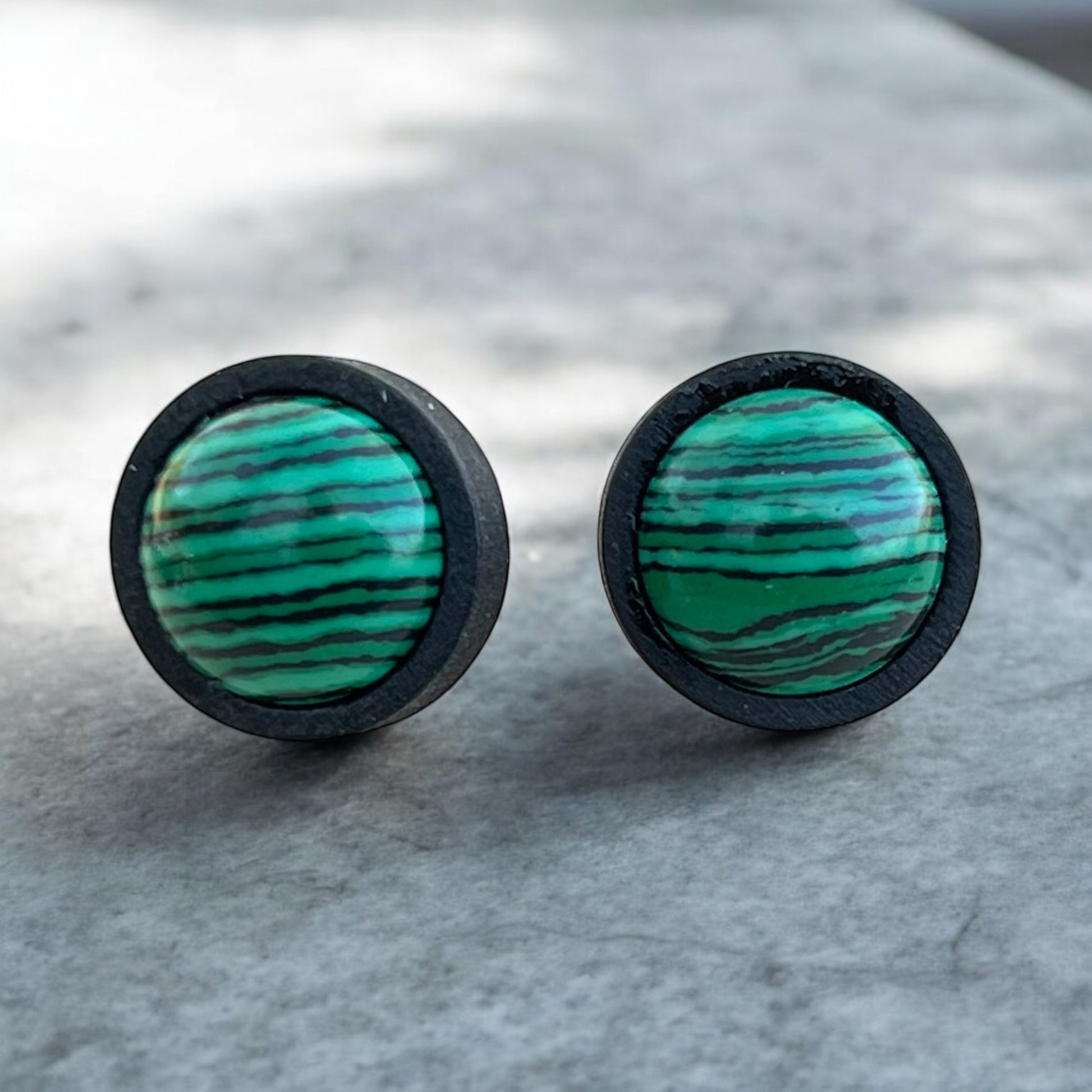 Green stone stud earrings flat lay with wood bezel and striped design