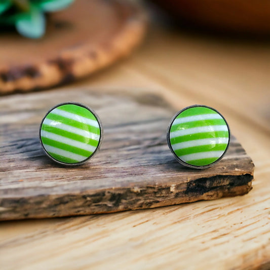 Green and white striped earrings on a wooden surface