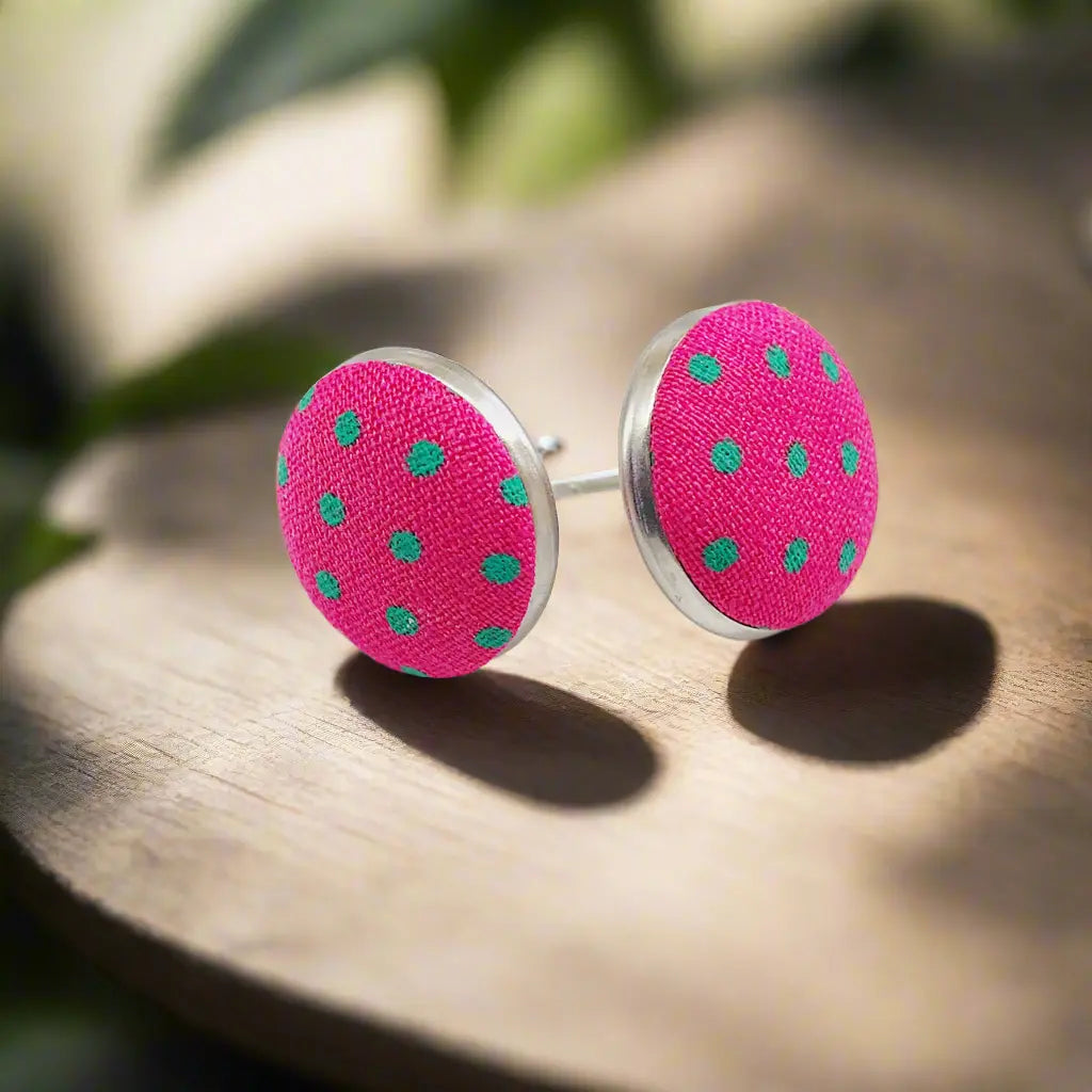 Pink earrings with green polka dots on a wooden surface