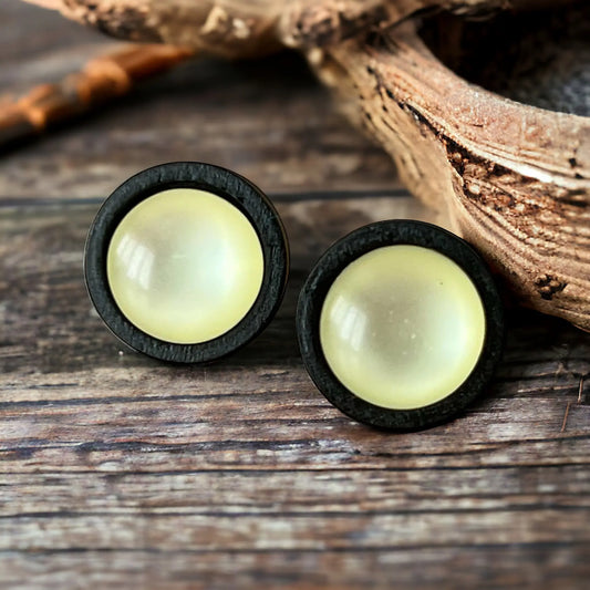 Pair of earrings with black rims and yellow centers on a wooden surface
