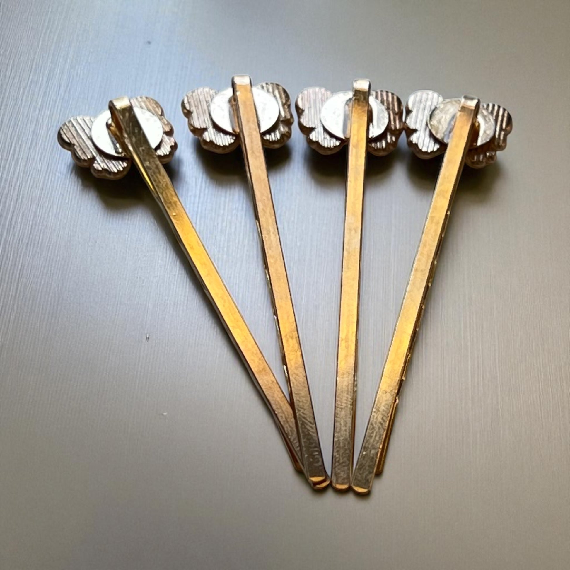 Backside of gold metal butterfly bobby pins on a metallic surface