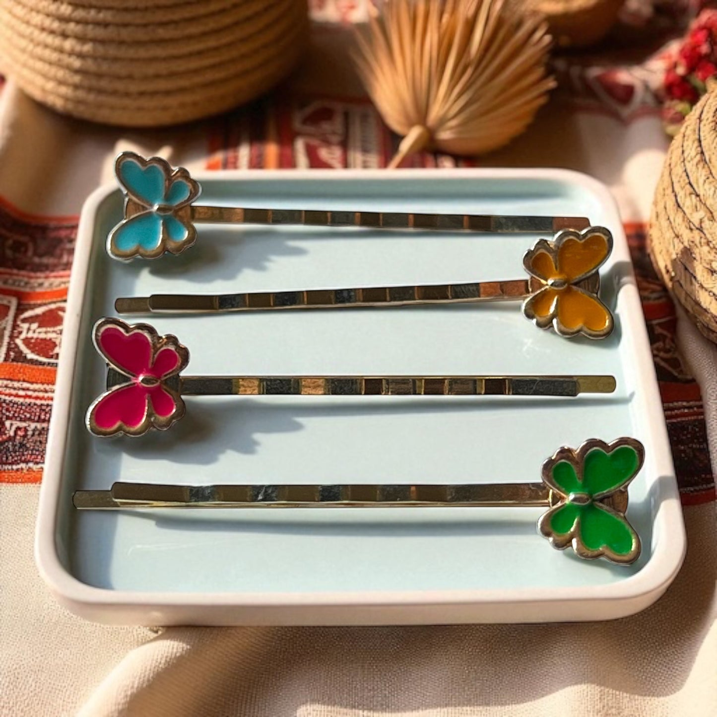 Set of butterfly-themed hairpins on a decorative tray with a colorful background