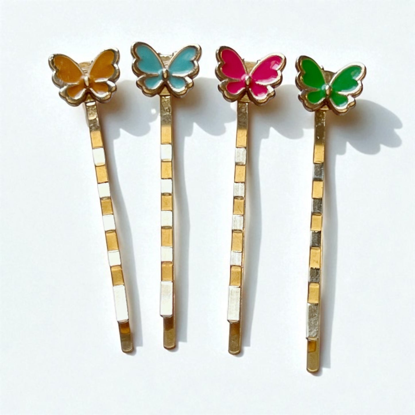Four butterfly-themed hair pins with colorful wings on a white background