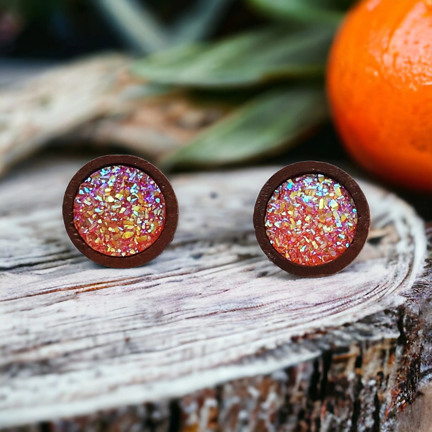 Round orange druzy wood stud earrings displayed on a rustic wood surface