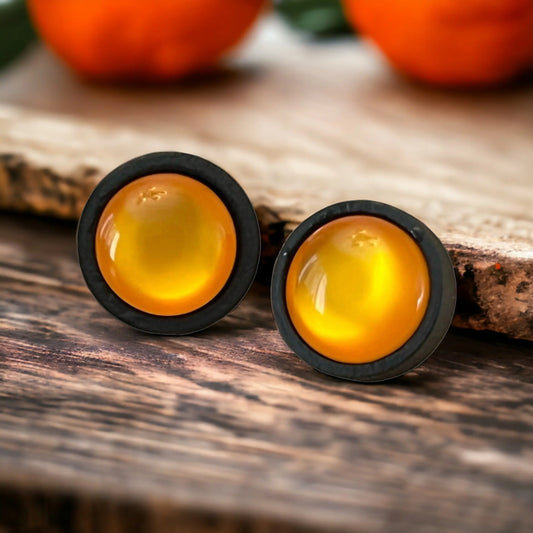 Pair of earrings with orange centers on a wooden surface
