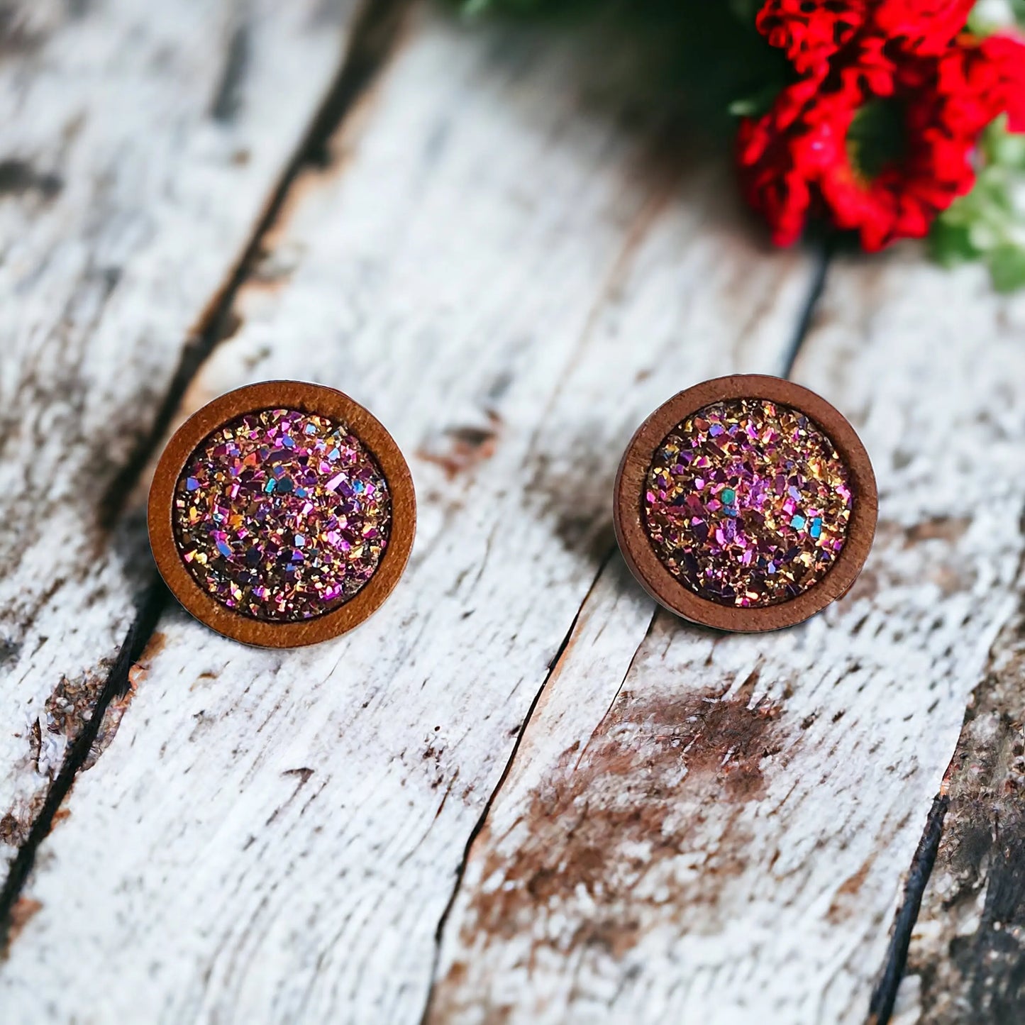 Round pink glitter druzy wood stud earrings displayed on a boho white wood surface