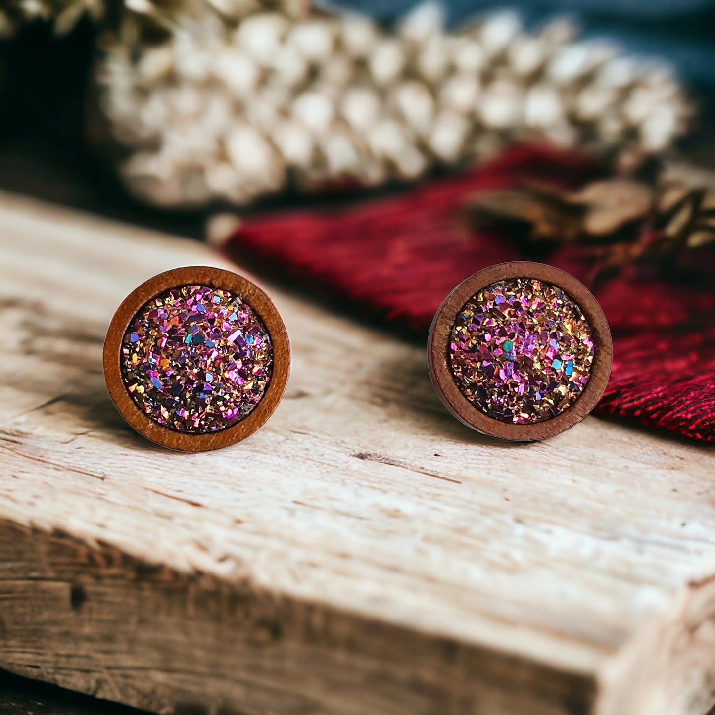Round pink glitter druzy wood stud earrings displayed on a rustic wood surface