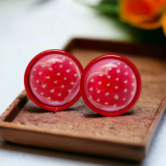 Red earrings with white hearts on a wooden surface