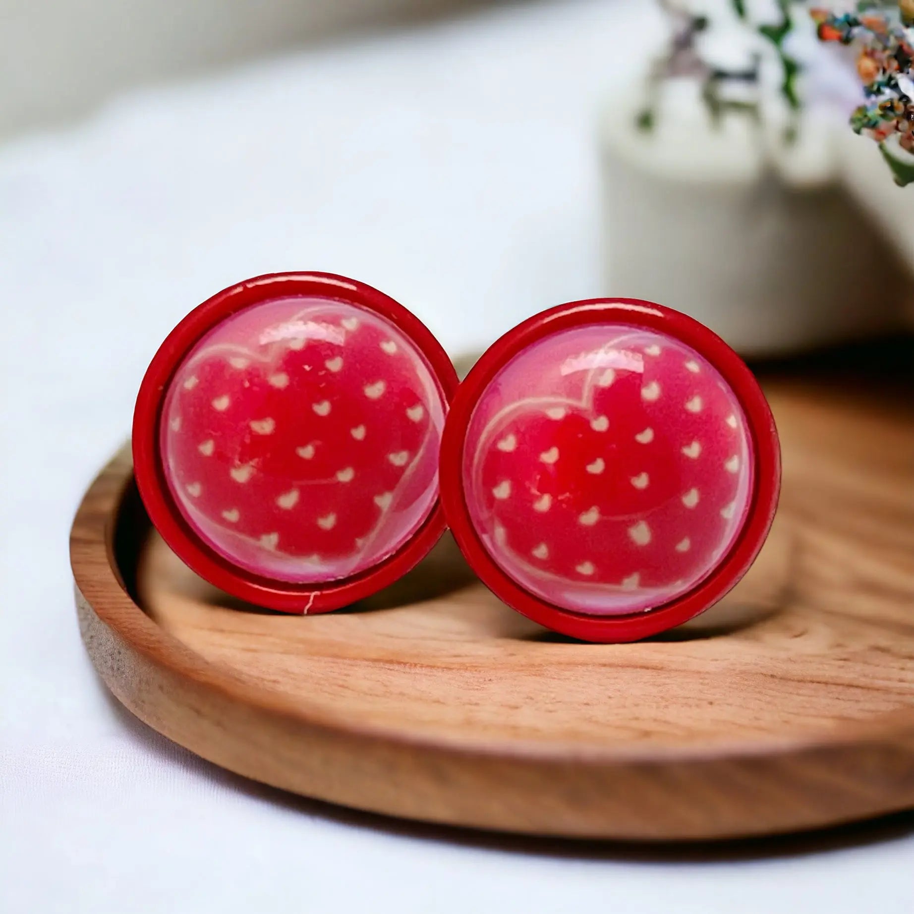 Red earrings with tiny white heart on a wooden plate