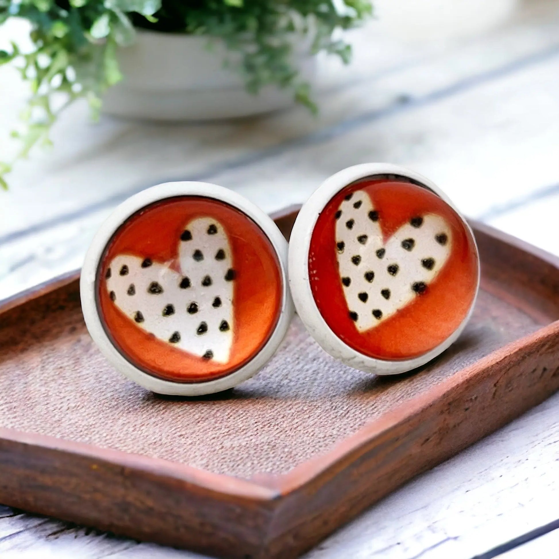 Pair of earrings with heart design on a wooden tray