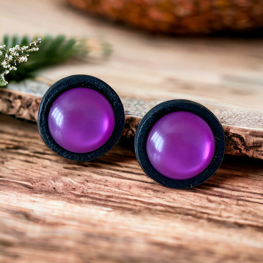 Purple round earrings with black rims on a wooden surface