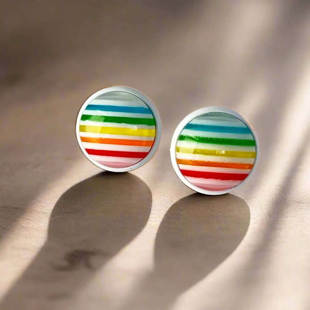 Pair of round earrings with colorful striped design on a beige background