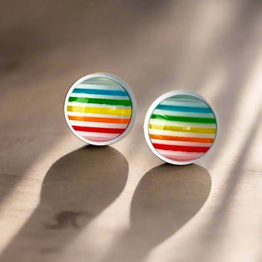 Pair of round earrings with colorful striped design on a beige background