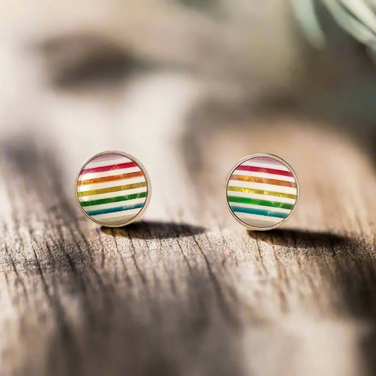 Round rainbow striped stud earrings in a silver-tone setting displayed on a wood surface