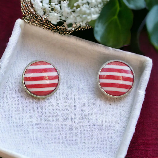 Round red and white striped stud earrings in a silver-tone setting displayed on a white tray