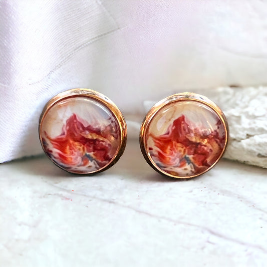 Rose gold setting stud earrings with glossy marbled resin in red, blush, and white on marble