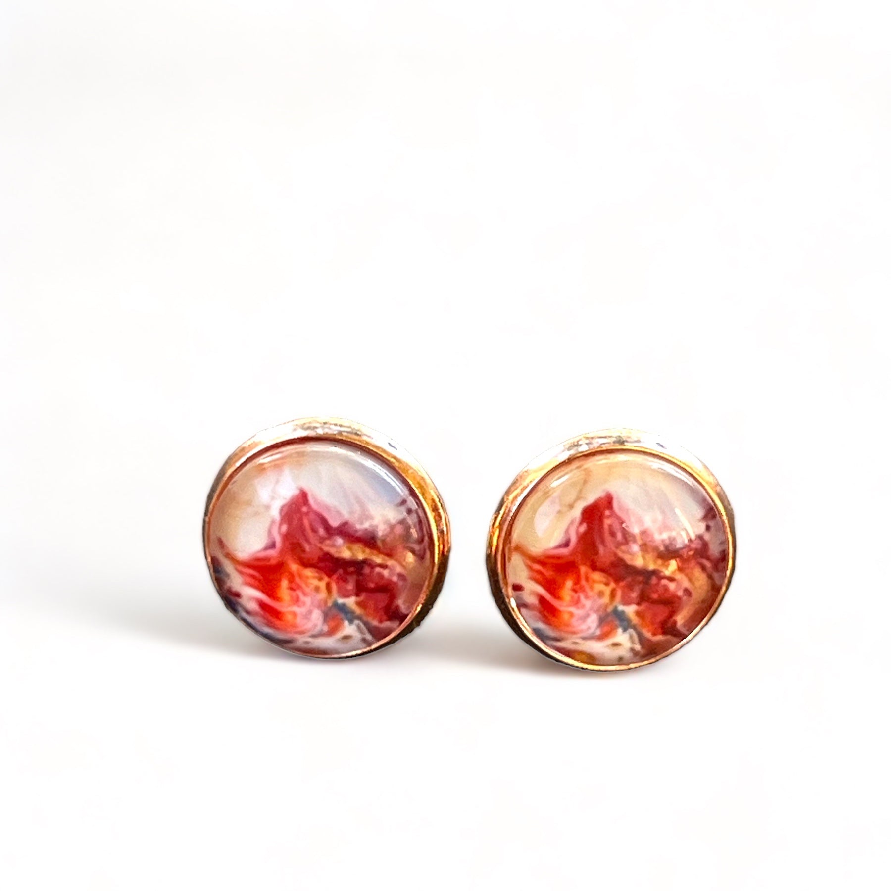 Rose gold setting stud earrings with glossy marbled resin in red, blush, and white on white background