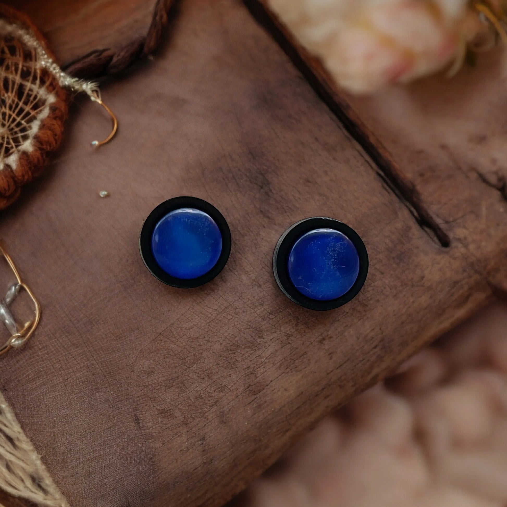 Blue circular earrings with black rims on a wooden surface