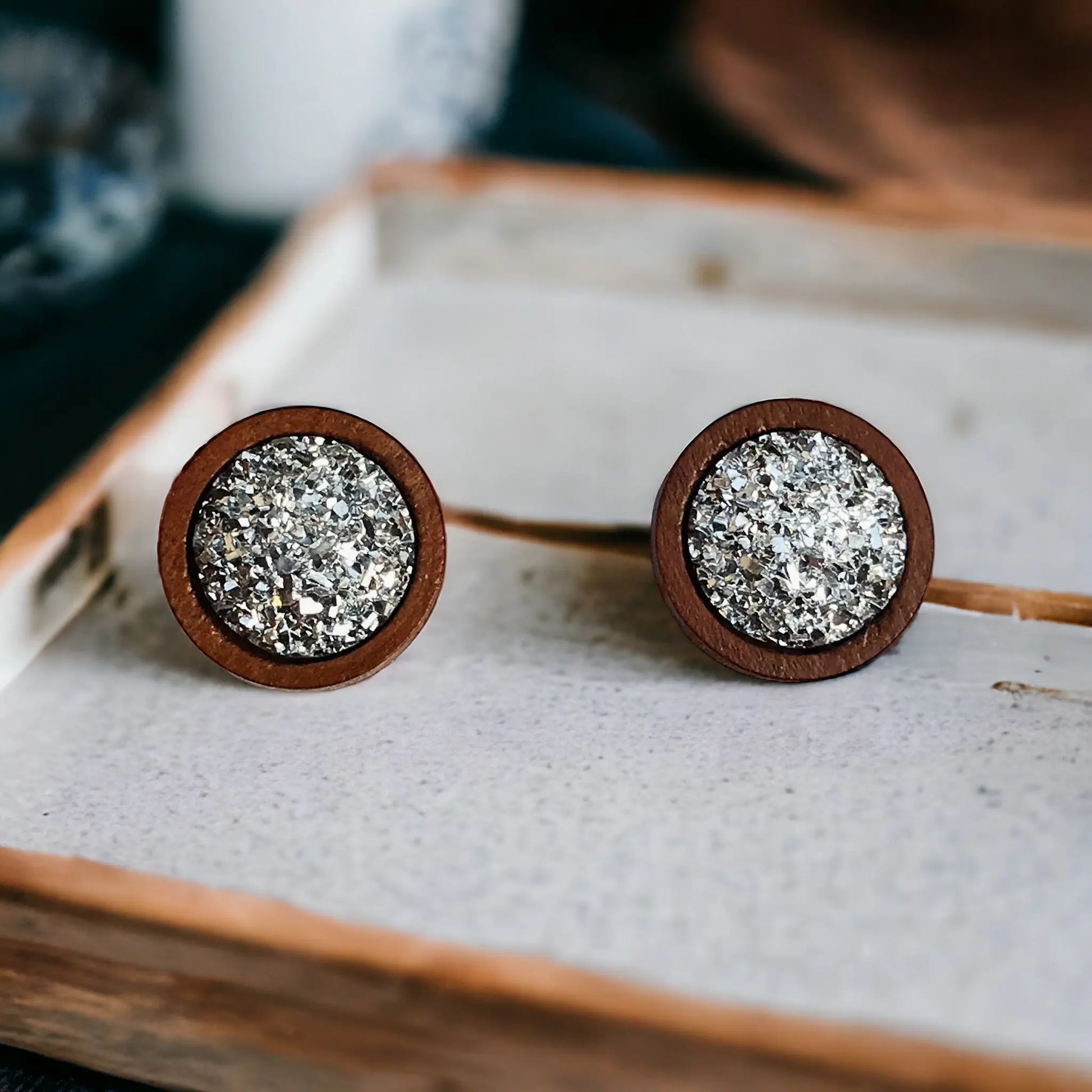 Round silver druzy wood stud earrings displayed on a rustic tray