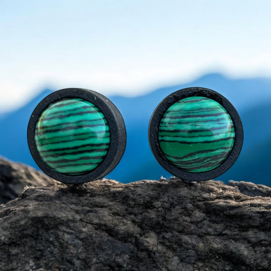 Close-up of striped green stud earrings in black wood bezel