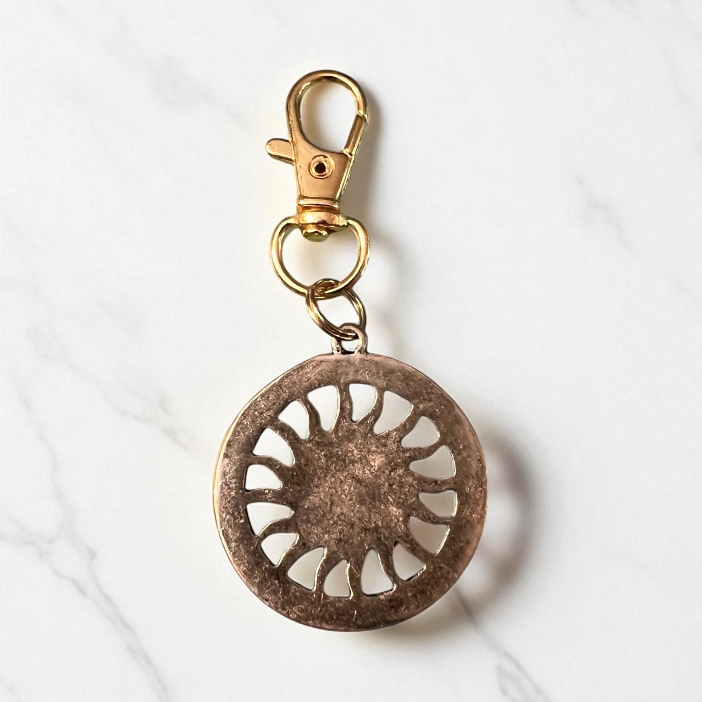 Back side of Bronze keychain with decorative Sun design on a white background