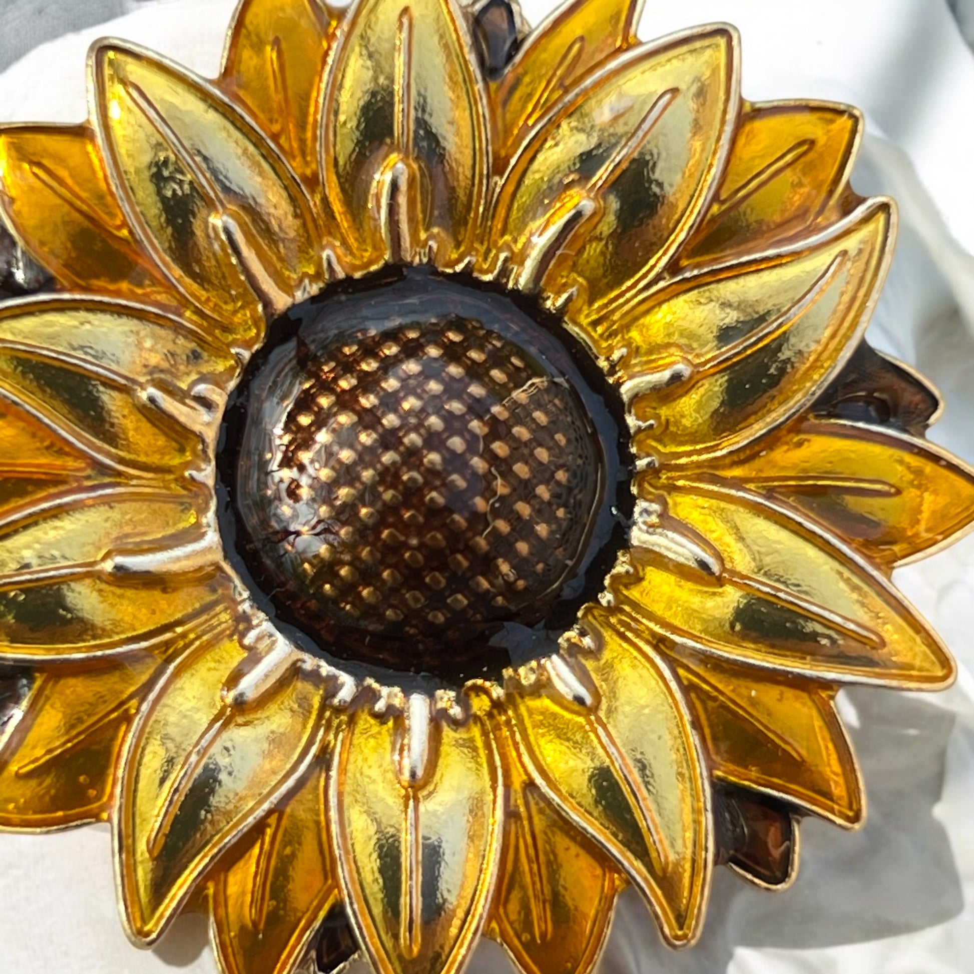 Close-up of gold and brown sunflower charm on marble background
