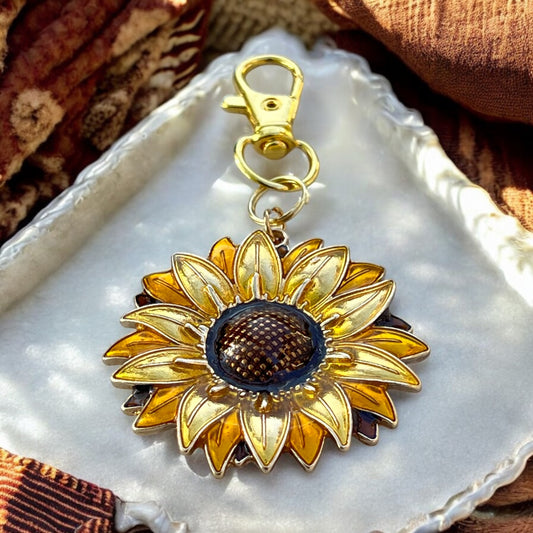 Sunflower purse charm with gold petals and brown center on white dish
