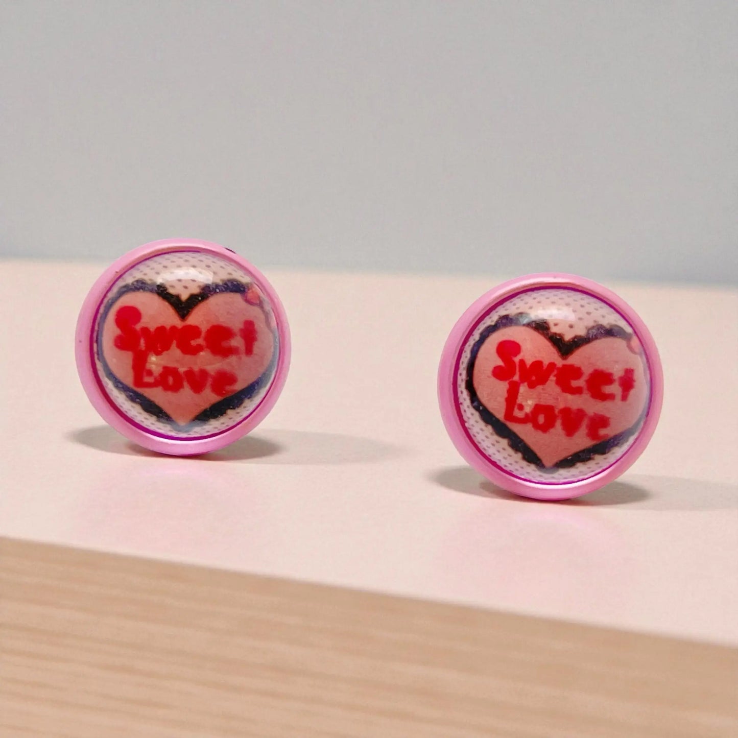 Heart-shaped earrings with 'Sweet Love' text on a light background