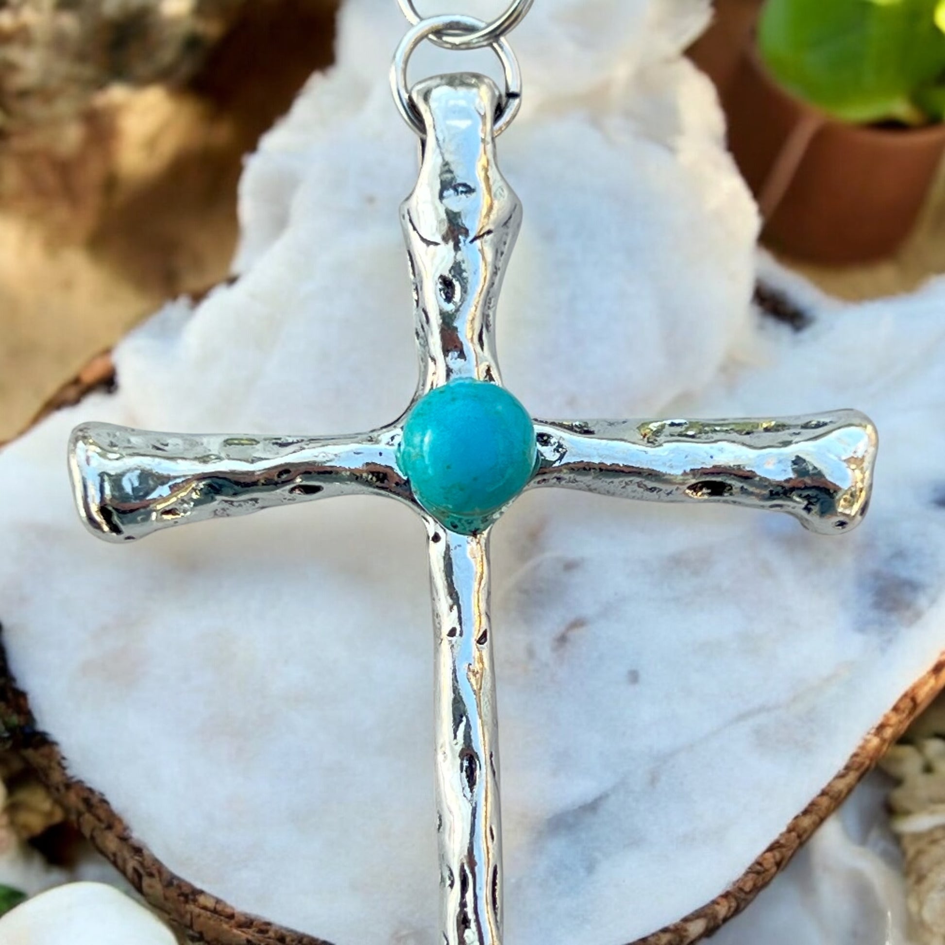 Styled photo of turquoise boho cross charm with western accessories