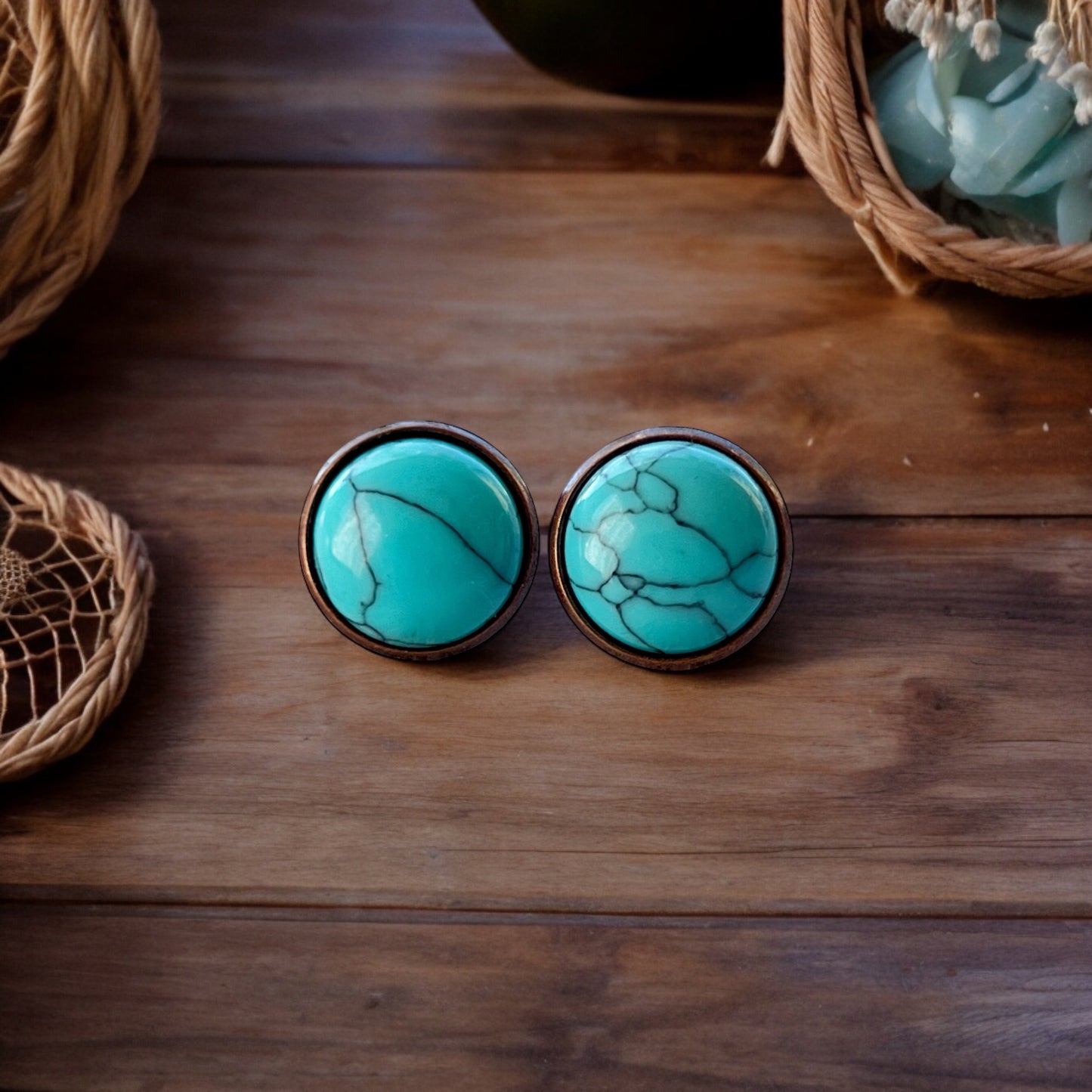 Round turquoise copper stud earrings displayed on a dark wood background