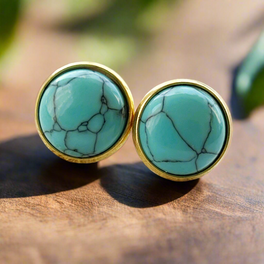 Round turquoise gold stud earrings displayed on a light wood background