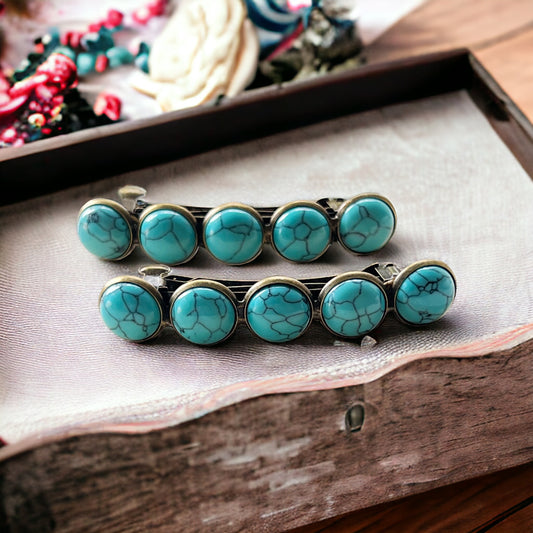  Set of two bronze western hair barrettes with faux turquoise stones on a wood display