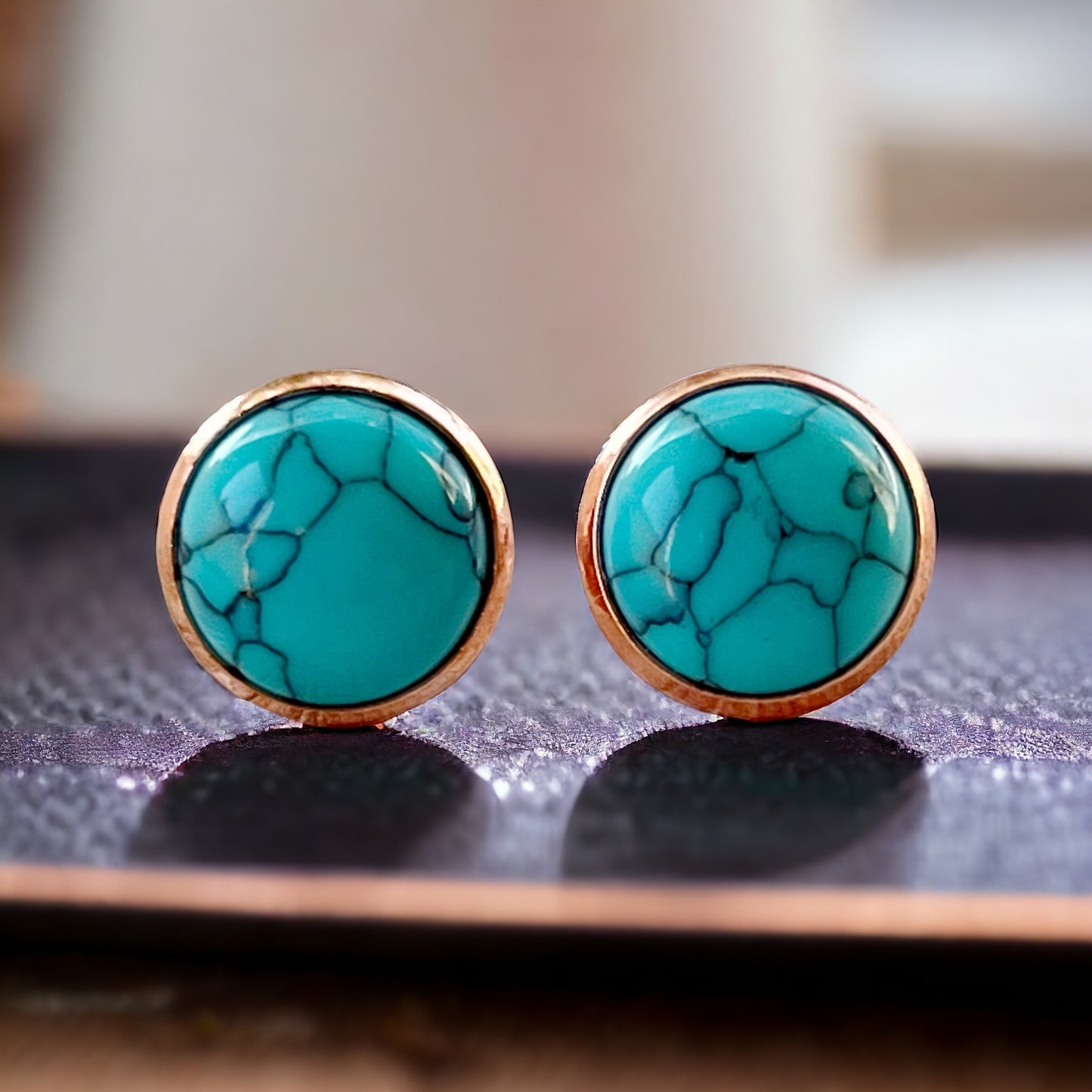 Round turquoise rose gold stud earrings displayed on a dark surface