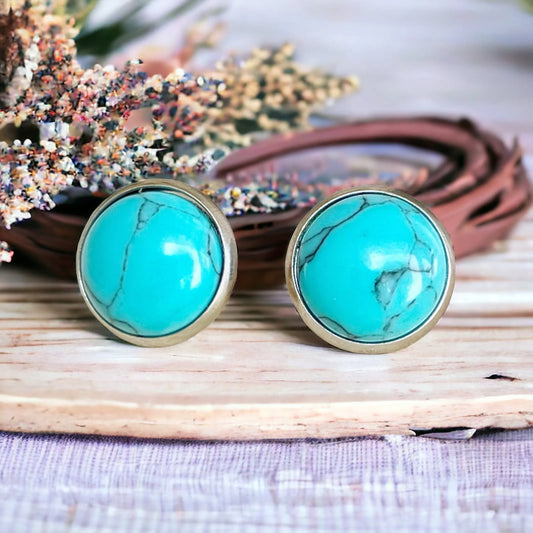 Round turquoise stud earrings in a western boho setting displayed on a wood surface