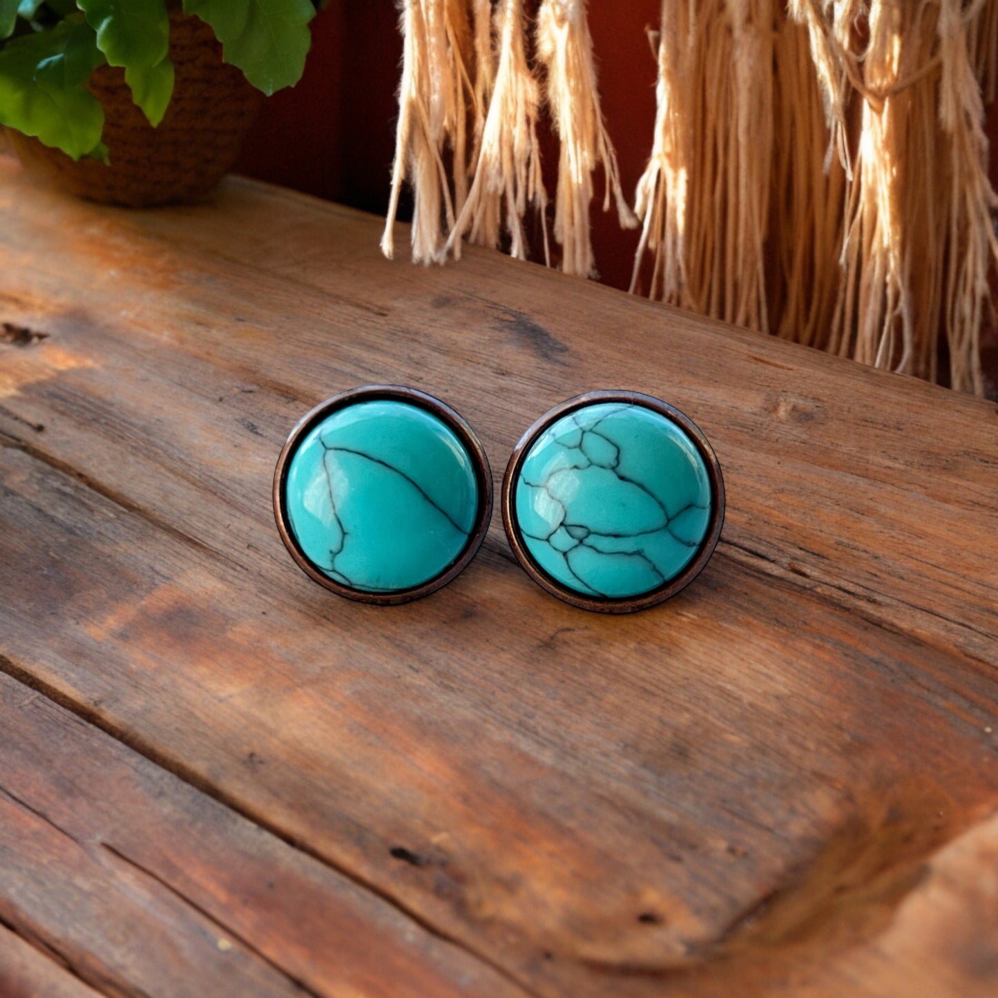 Round turquoise copper stud earrings displayed on a light wood background