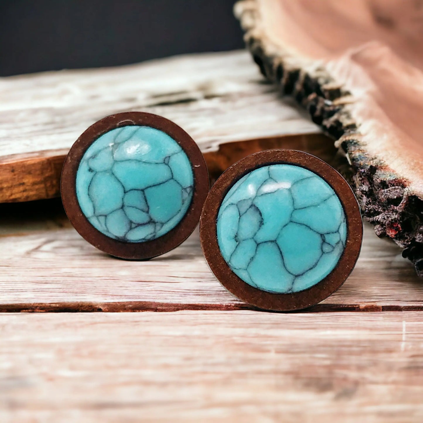Close-Up of round turquoise wood stud earrings displayed on a rustic wood surface