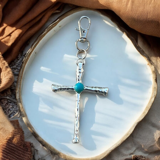 Western-inspired turquoise cross keychain displayed on handbag
