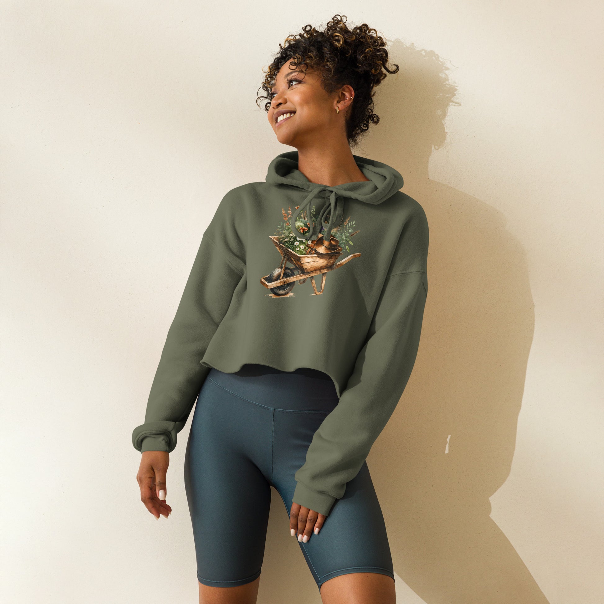 Model wearing military green hoodie with wildflower garden wheelbarrow print