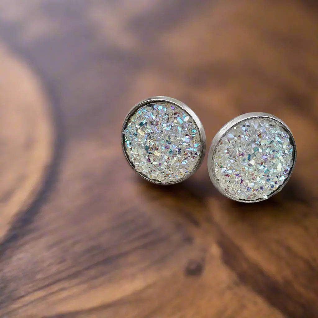 Round white iridescent druzy stud earrings in a silver-tone setting displayed on a wood surface