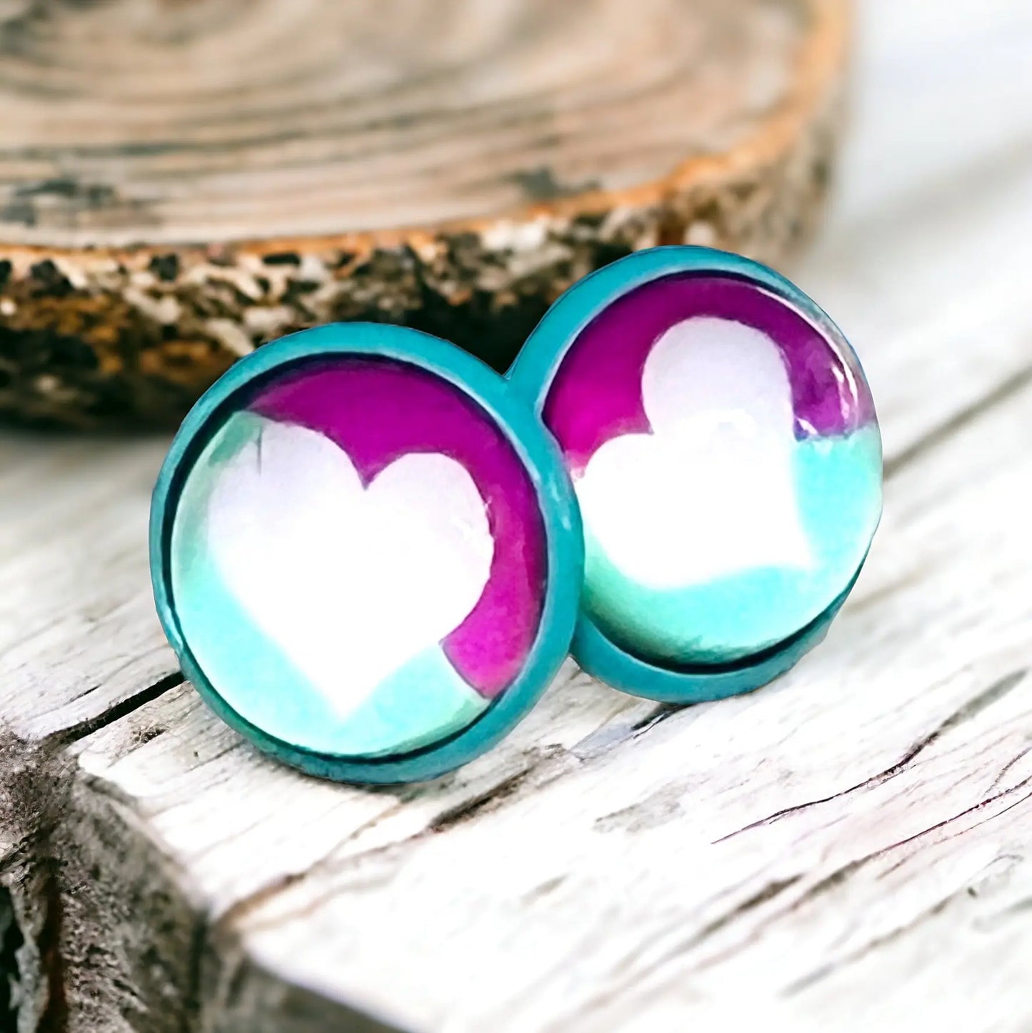 Pair of heart-shaped earrings with teal and purple gradient on a boho wooden surface