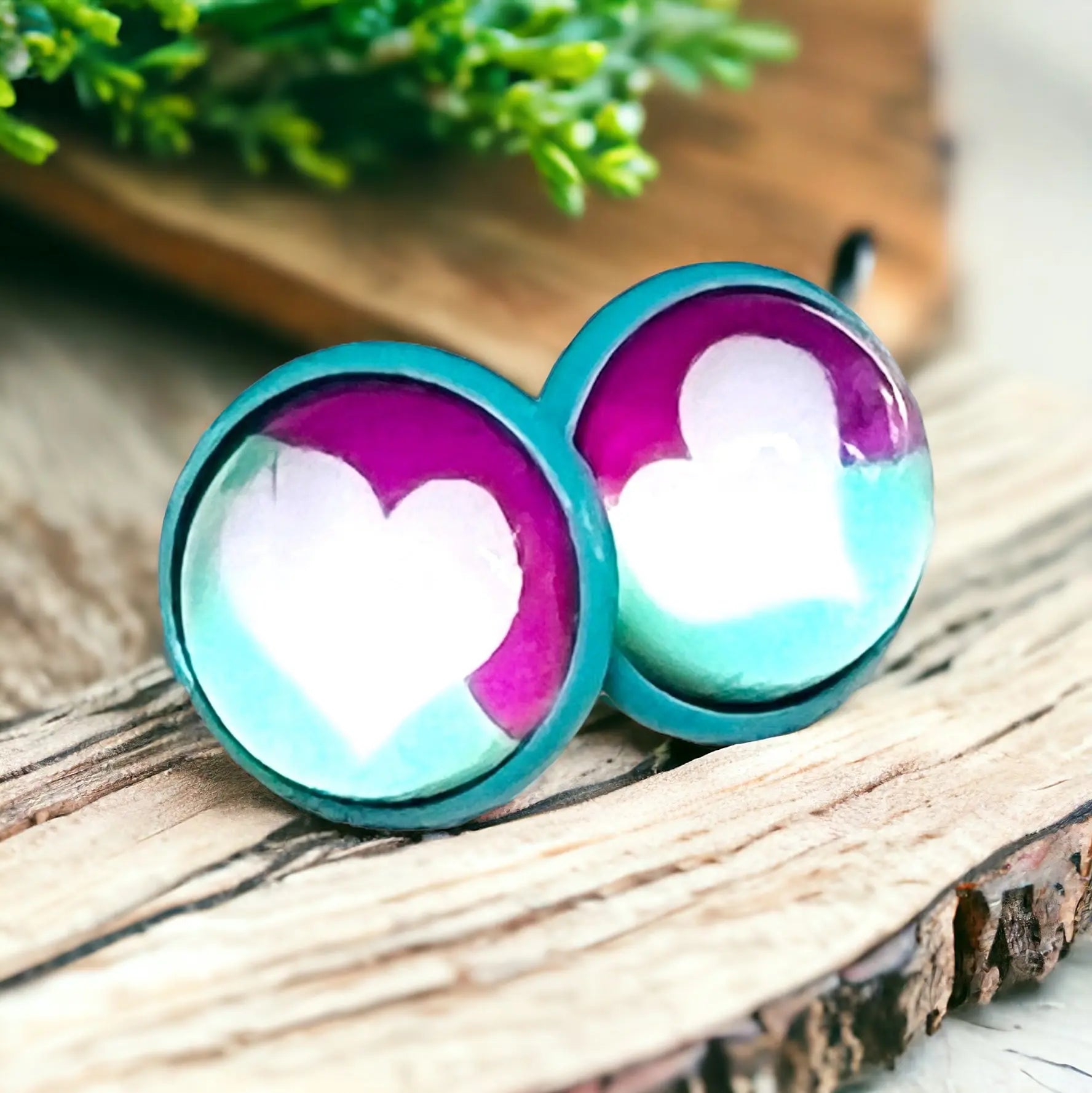 Heart-shaped earrings with teal and purple gradient on a wooden surface.