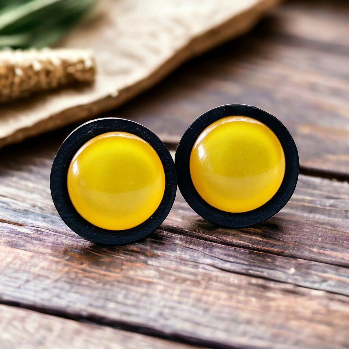 Yellow round earrings with black borders on a wooden surface