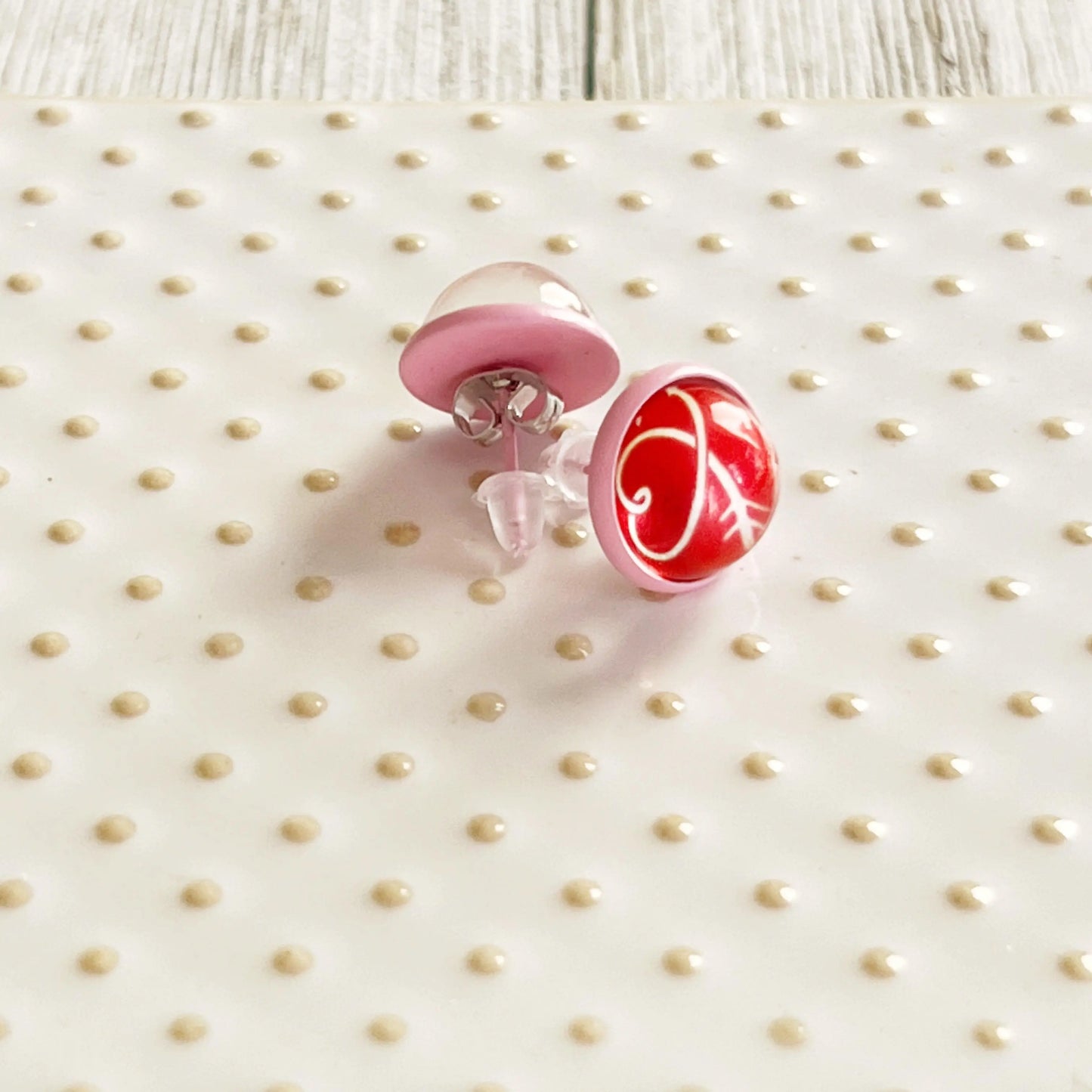 Pair of pink and red heart earrings on a polka dot surface
