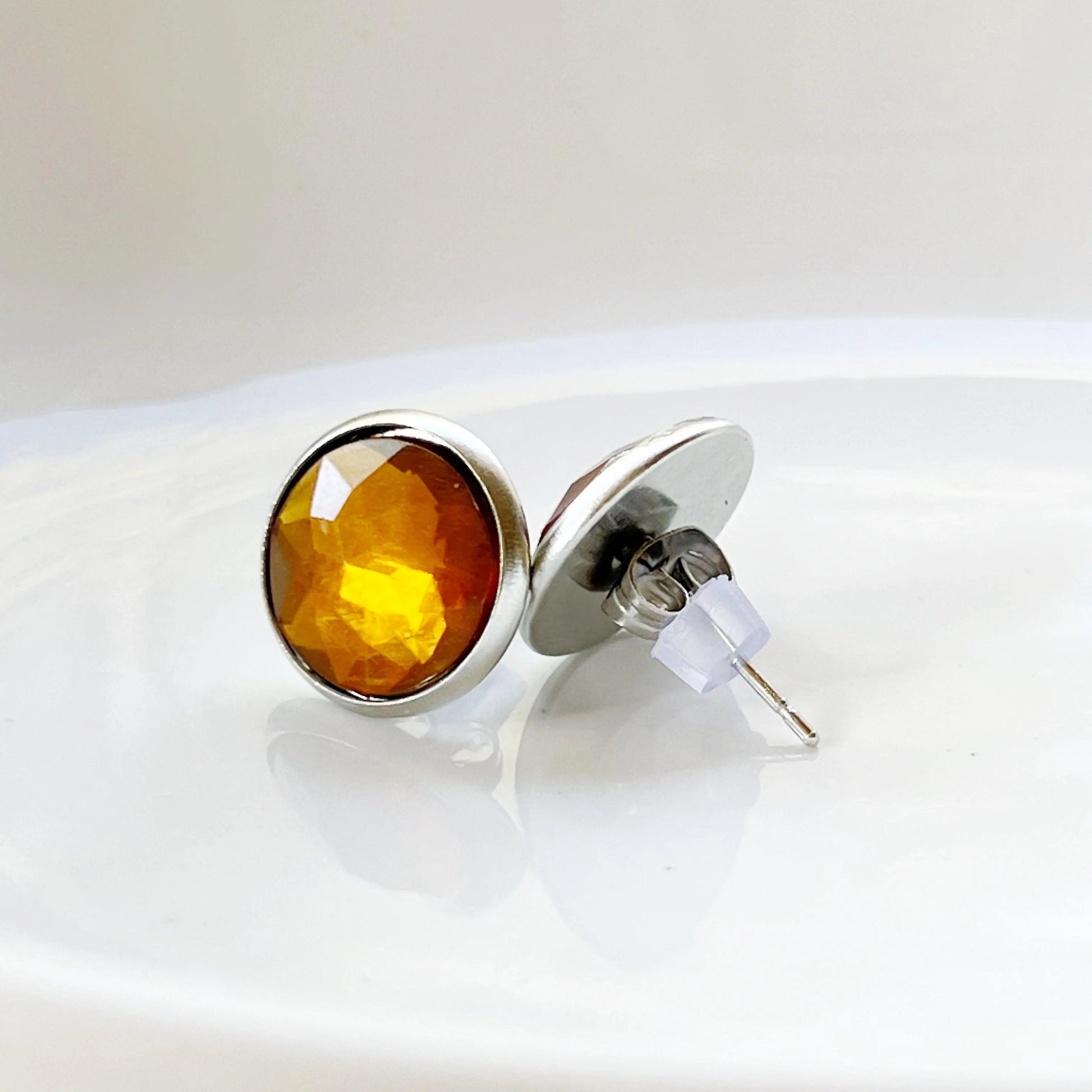 Silver earrings with amber-colored gemstones on a white background