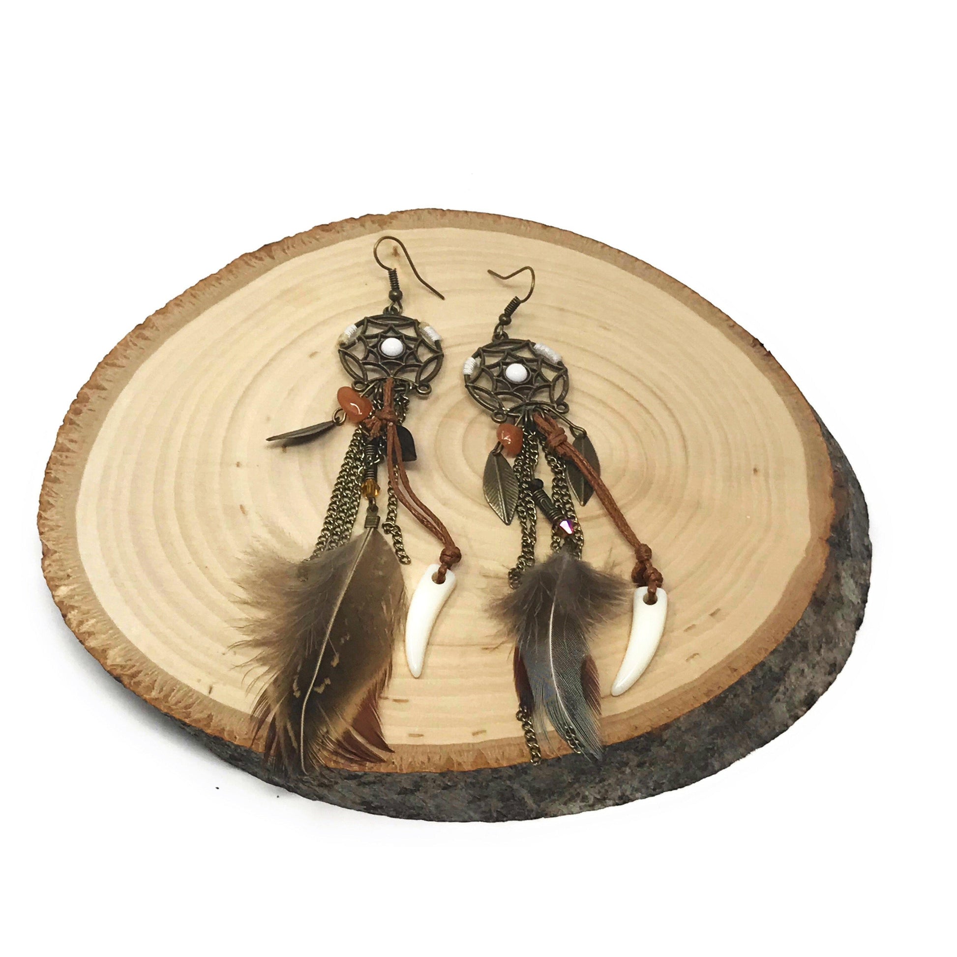 Flat lay of dream catcher feather earrings with faux feathers and metal charm