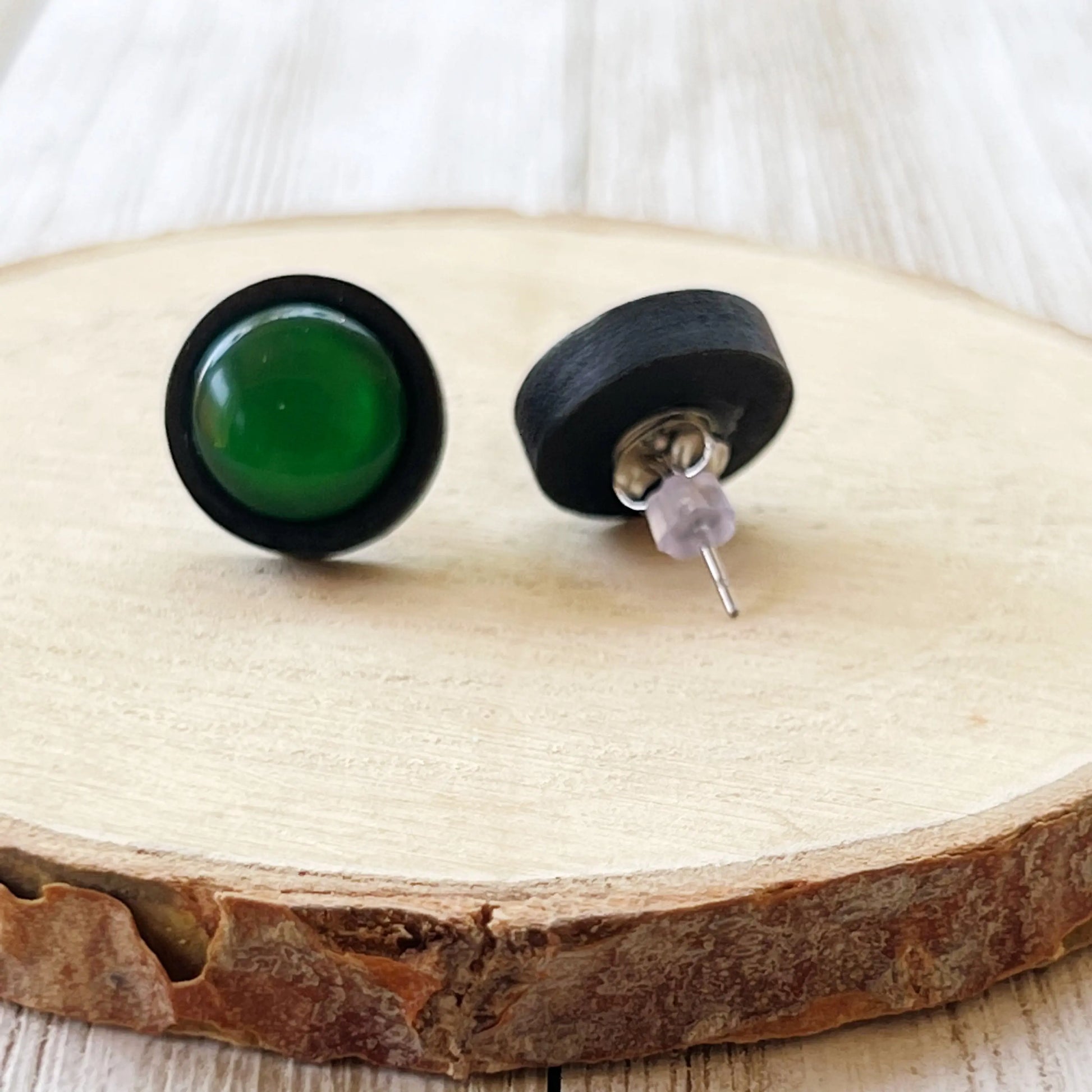 Back of Green round earrings with black bases on a wooden surface